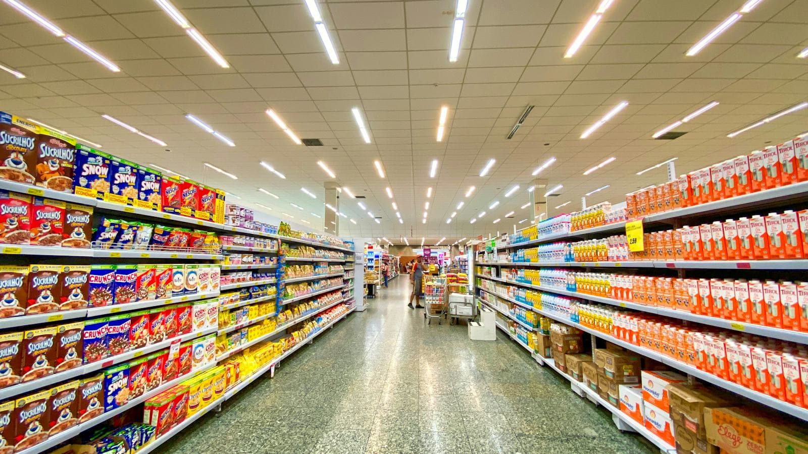 Pasillo de supermercado con góndolas de cereales y leches con sus etiquetas de precio